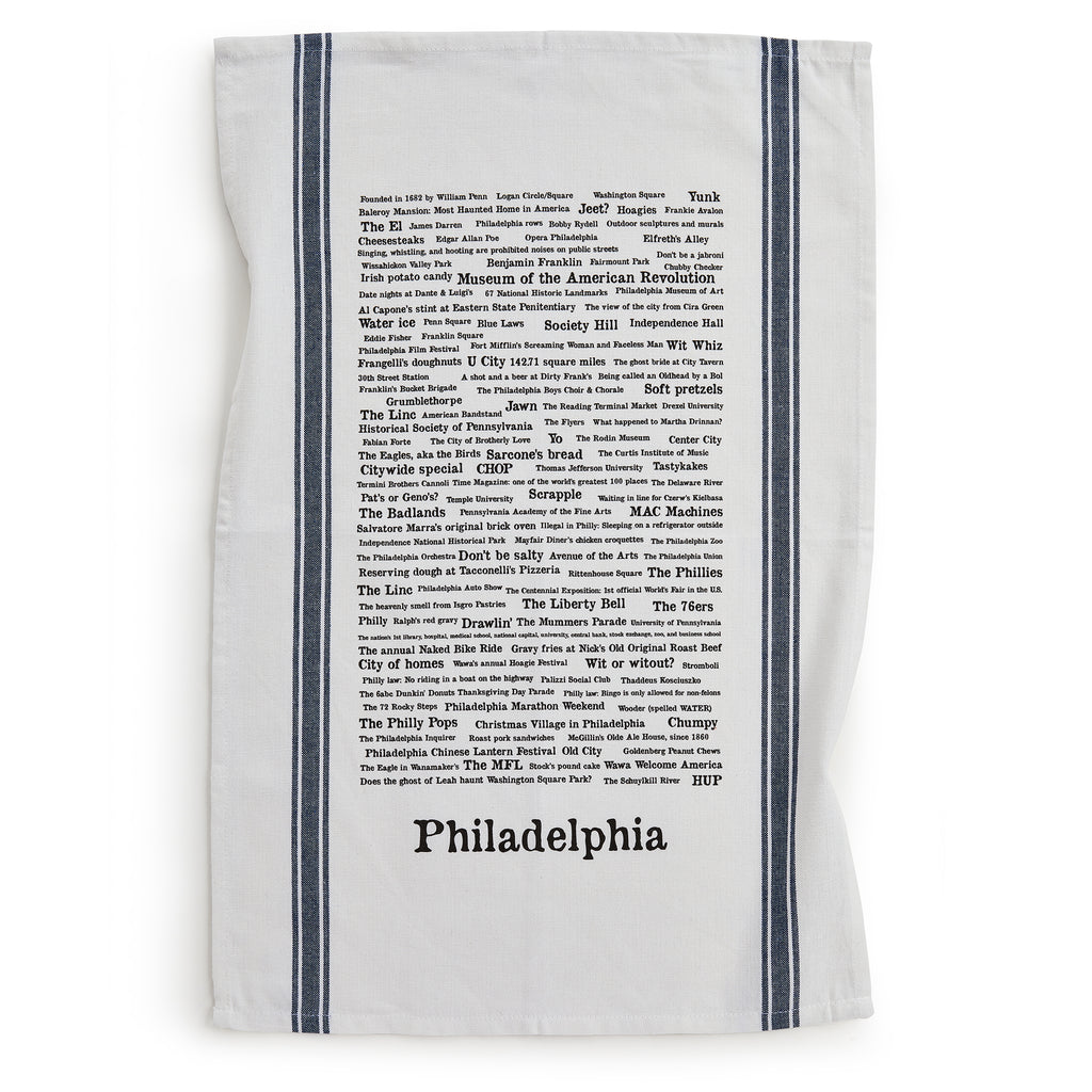 The Philadelphia Tea Towel features black typographic trivia about the city's landmarks, sports teams, foods, and neighborhoods. Handprinted with two vertical dark stripes on each side.