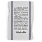 The Philadelphia Tea Towel features black typographic trivia about the city's landmarks, sports teams, foods, and neighborhoods. Handprinted with two vertical dark stripes on each side.