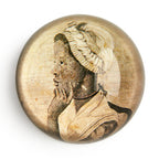 The Phillis Wheatley Glass Paperweight features a sepia-toned, vintage-style profile illustration of the African American poet with a headscarf, resting her chin on her hand against a plain white background.