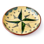 The Star Plate is a round ceramic sgraffito dish inspired by Pennsylvania German pottery, featuring a large green and yellow star in the center, small black stars surrounding it, and a green and brown decorative border.