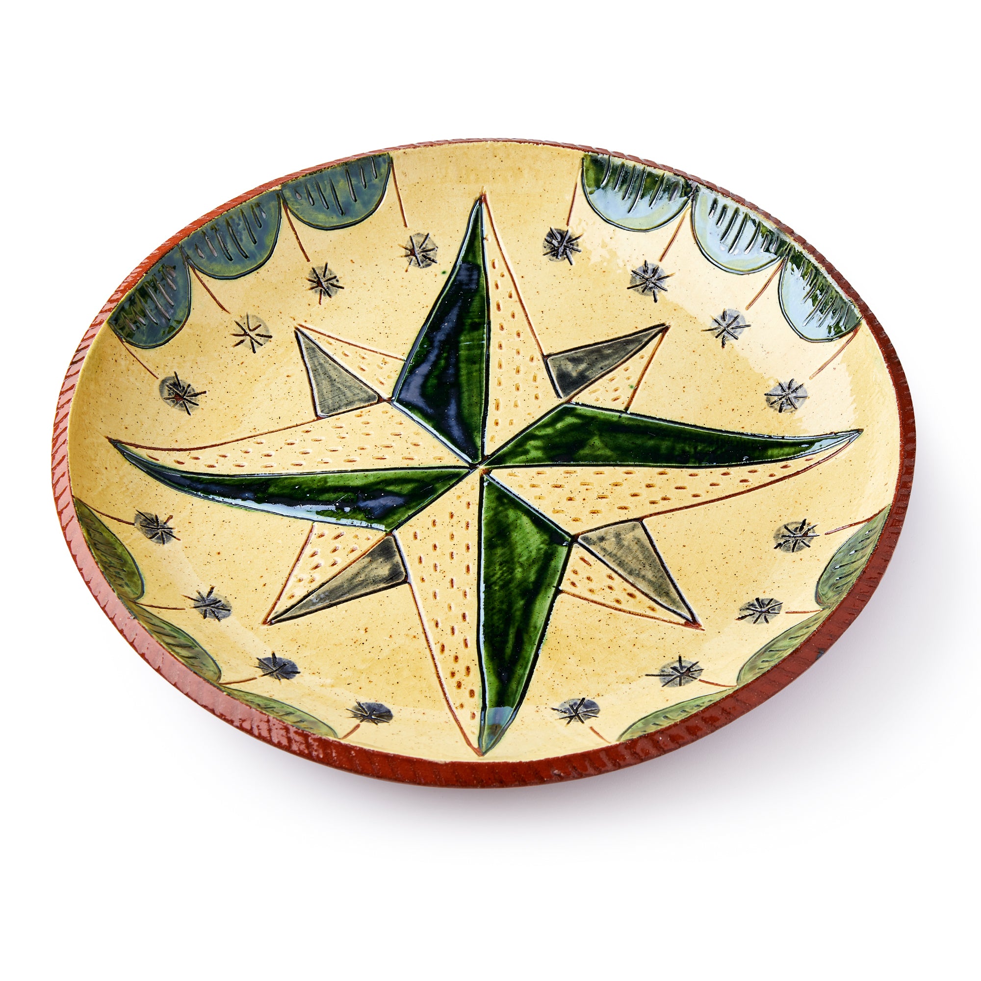 The Star Plate is a round ceramic sgraffito dish inspired by Pennsylvania German pottery, featuring a large green and yellow star in the center, small black stars surrounding it, and a green and brown decorative border.