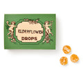 A green box of Elderflower Drops sits beside three yellow cough drops on a white background.