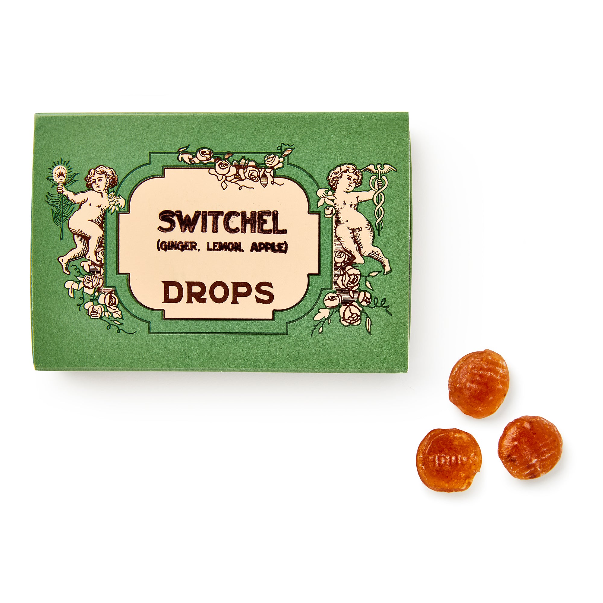 A green box labeled Switchel Drops by Shane Confectionery, adorned with vintage cherubs, is placed next to three round amber handcrafted candy drops on a white background.
