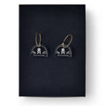 Skull and Crossbone Earrings: Clear acrylic earrings with gold hoops, each featuring a white skull-and-crossbones design, displayed on black—ideal for fans of historical or Stamp Act-inspired jewelry.