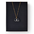 The Skull and Crossbones Necklace features a gold chain and black pendant, inspired by Stamp Act jewelry and colonial resistance symbols, displayed on a plain black rectangular box.