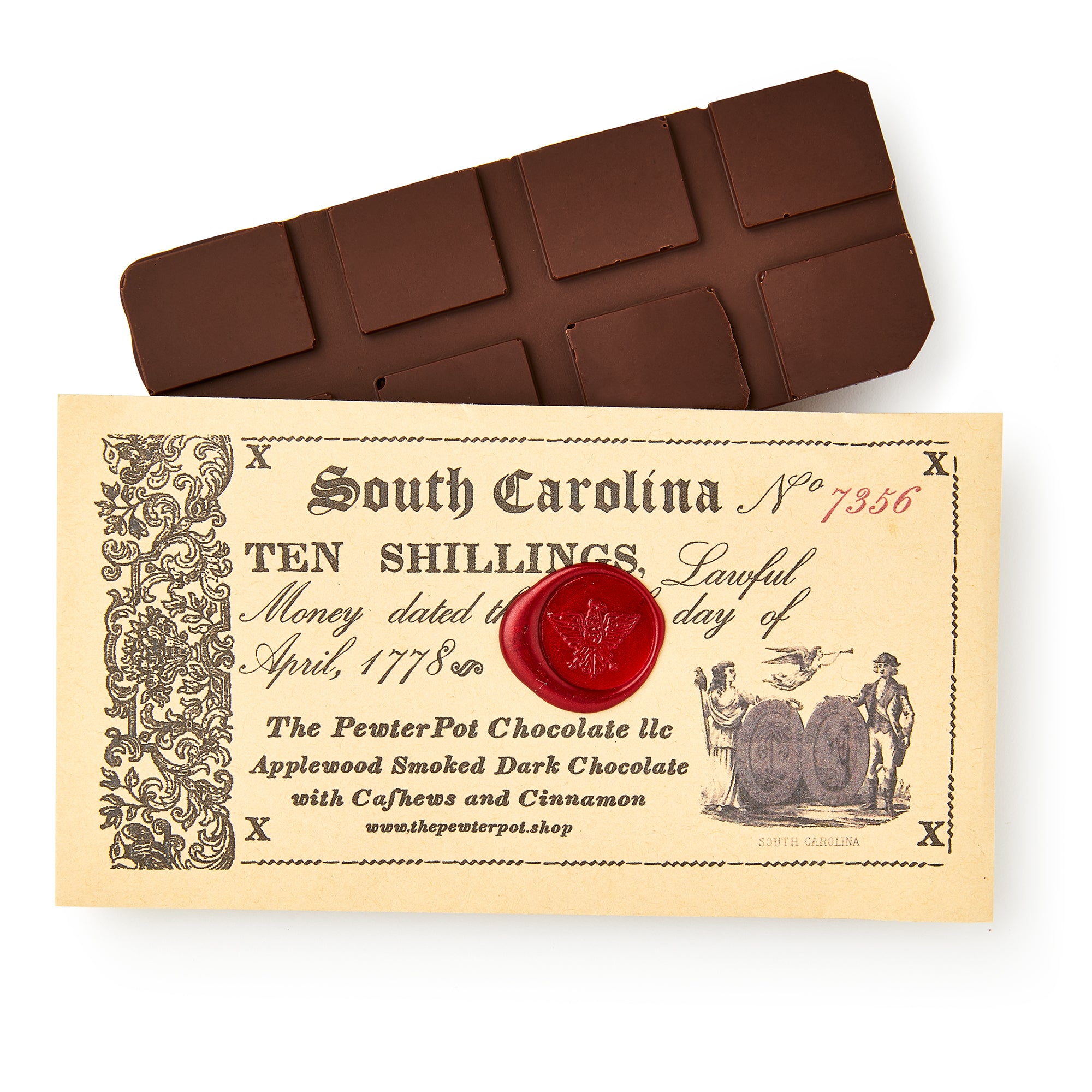 The South Carolina Chocolate Bar, made with smoked chocolate, rests on a vintage-inspired ten shilling note adorned with a red wax seal, old-style text, and illustrations of barrels and two men.