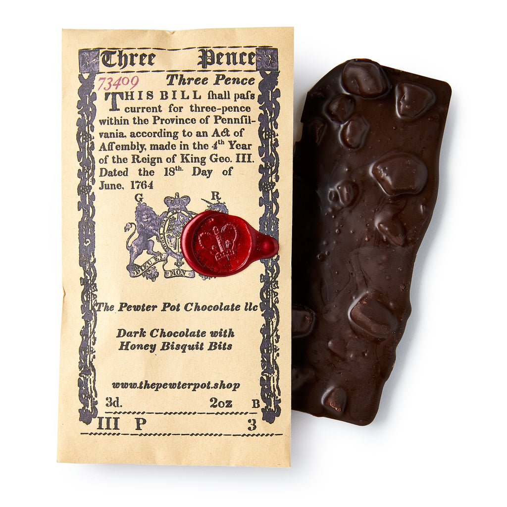 Dark chocolate bar with honey biscuit bits next to a vintage-style packaging label.