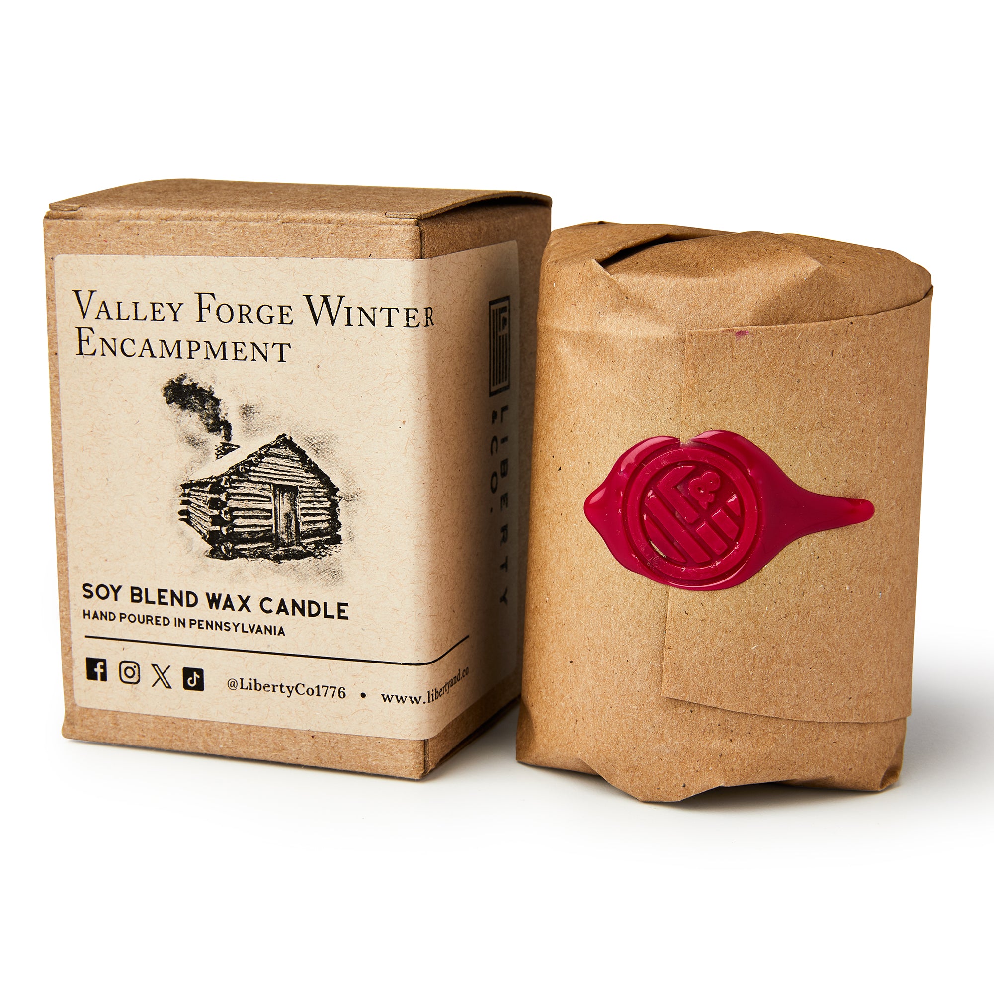 A brown box labeled Valley Forge Candle stands beside a candle wrapped in brown paper, sealed with red wax and a decorative stamp—both evoking a rustic, handcrafted look ideal for adding historical ambiance.