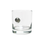 The Musket Ball Rocks Glass, handcrafted in the USA from clear glass and featuring a metallic musket ball-inspired sphere embedded in its side, is displayed against a plain white background.
