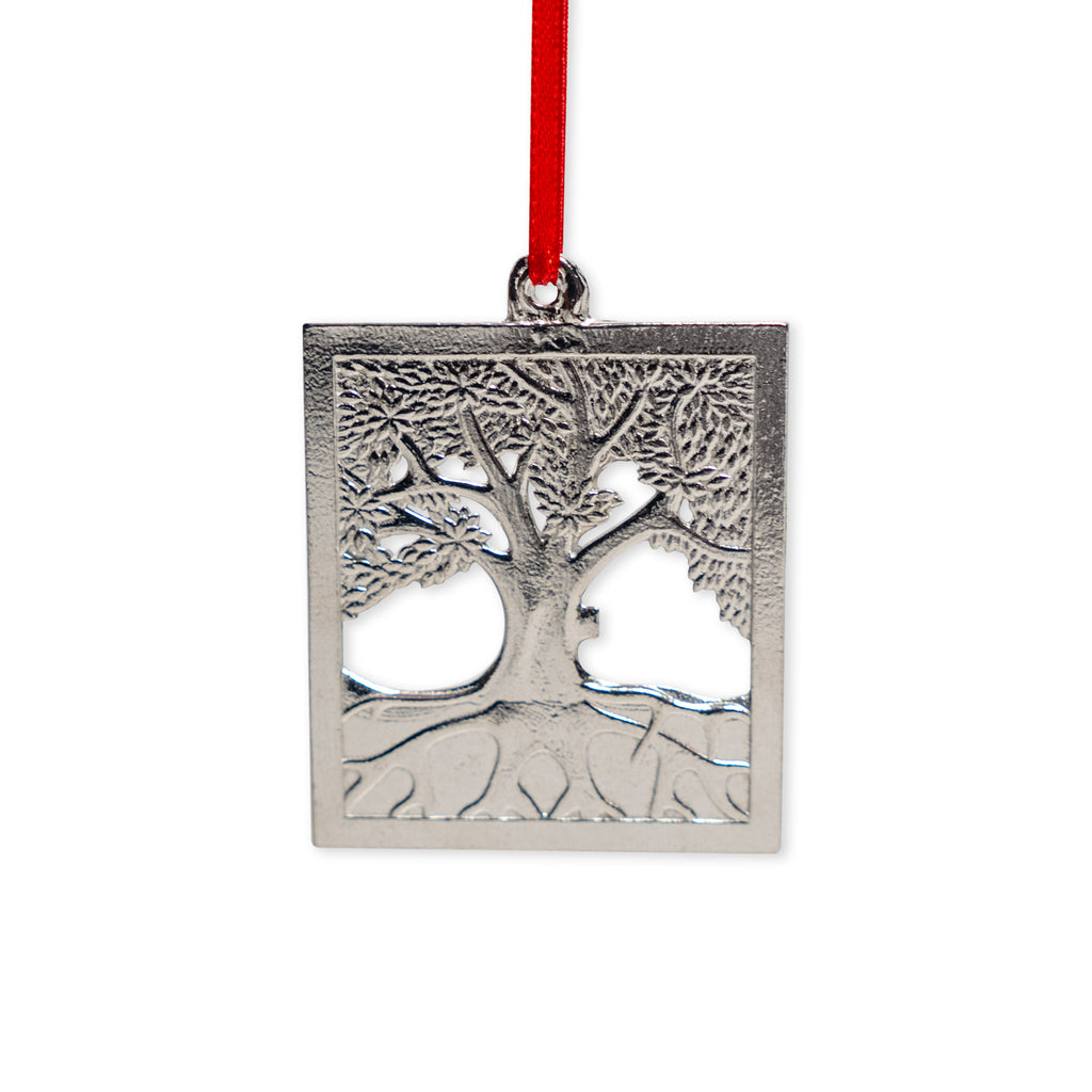 Introducing the Tree of Life Pewter Ornament—a handcrafted rectangular silver ornament made in North Carolina. Featuring a detailed tree of life design with visible roots and branches, this artisanal piece hangs elegantly from a red ribbon, beautifully showcasing expert craftsmanship.