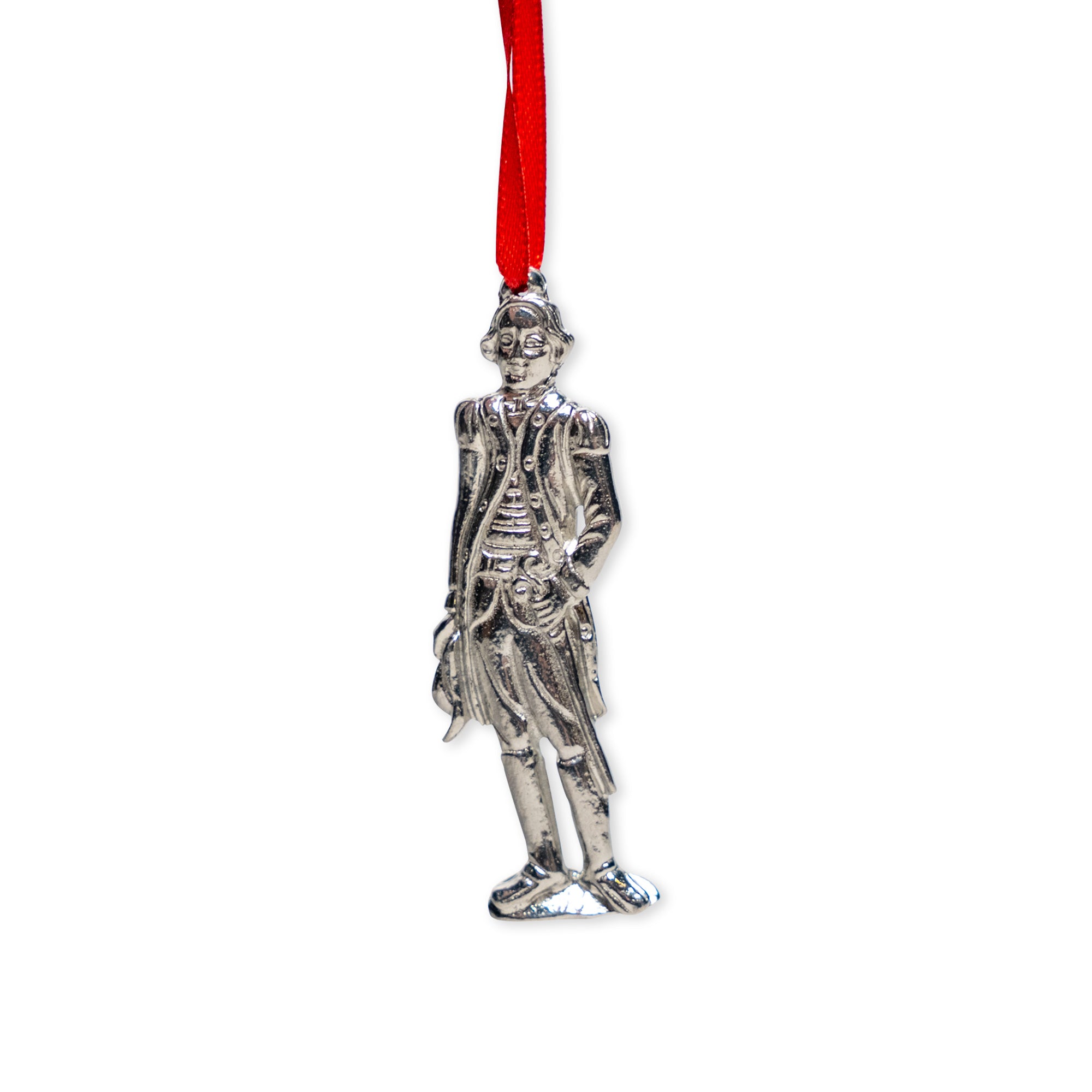 The George Washington Pewter Ornament, crafted in a silver-toned finish and depicting the historic figure in period attire, hangs from a vibrant red ribbon against a white background—making it an ideal decoration for celebrating patriotic holidays.