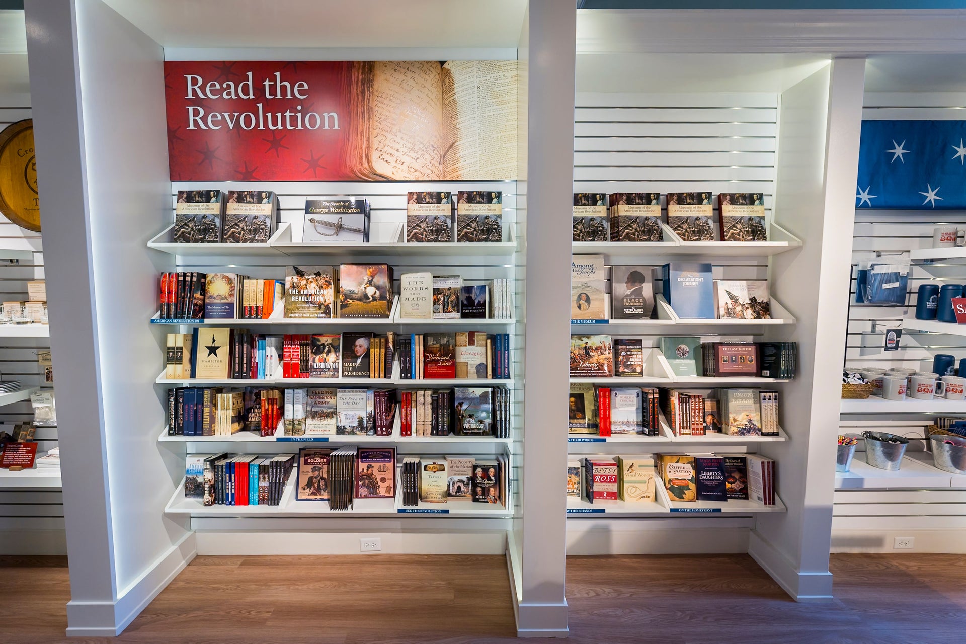 Bookshelf with books and a sign reading 'Read the Revolution' in a store setting.