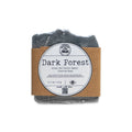 A black bar of Dark Forest Tallow Soap, crafted with grass-fed tallow and charcoal using the cold process method, is wrapped in brown paper and features a round white label, displayed against a white background.