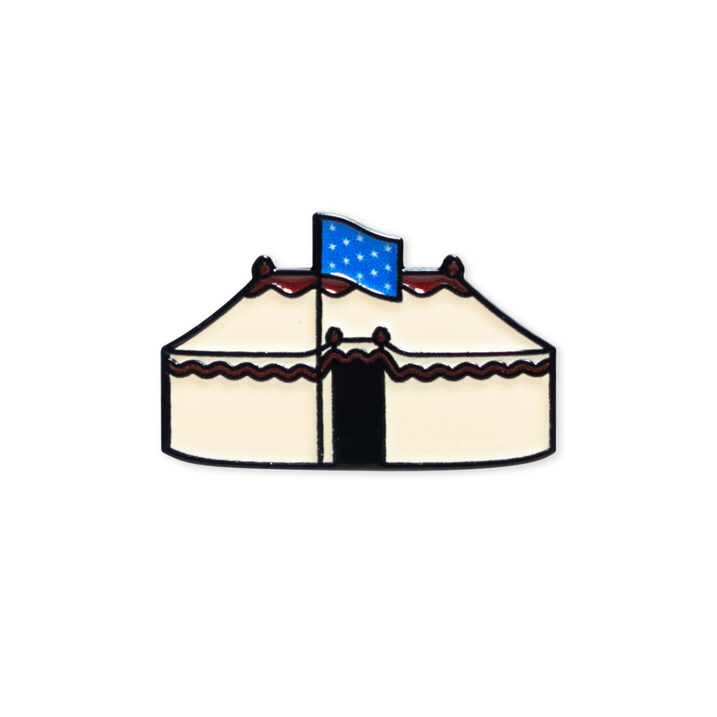 A simple illustration of the George Washington Tent Pin: a cream-colored tent with red trim and a blue flag with white stars on top, set against a plain white background.