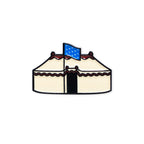 A simple illustration of the George Washington Tent Pin: a cream-colored tent with red trim and a blue flag with white stars on top, set against a plain white background.