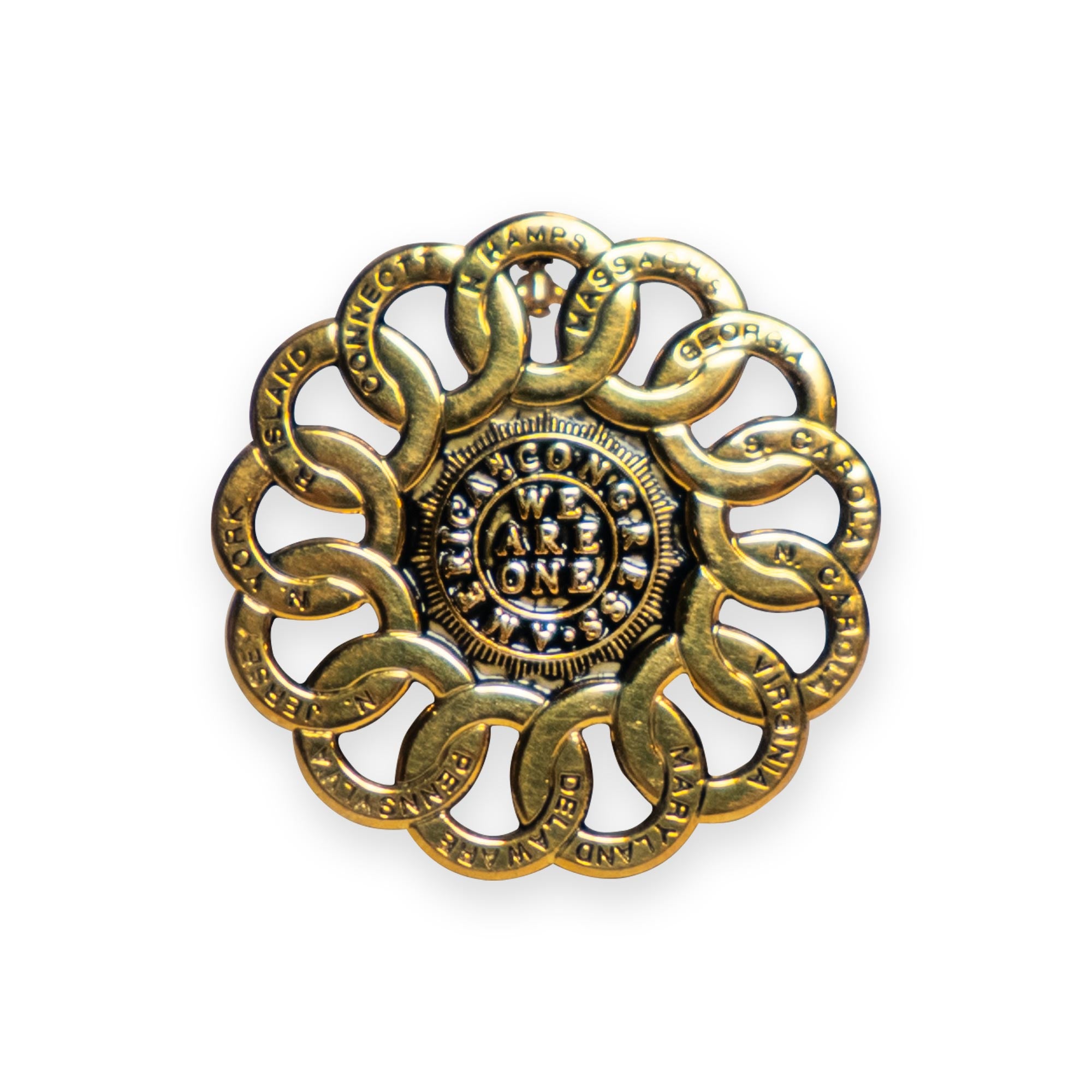 The Chain of States Pin & Pendant features interlocking gold rings, each engraved with the name of a U.S. state, forming a circle around a central disk inscribed with "WE ARE ONE"—a refined design inspired by the historic Chain of States emblem and currently on display at the Museum of the American Revolution.