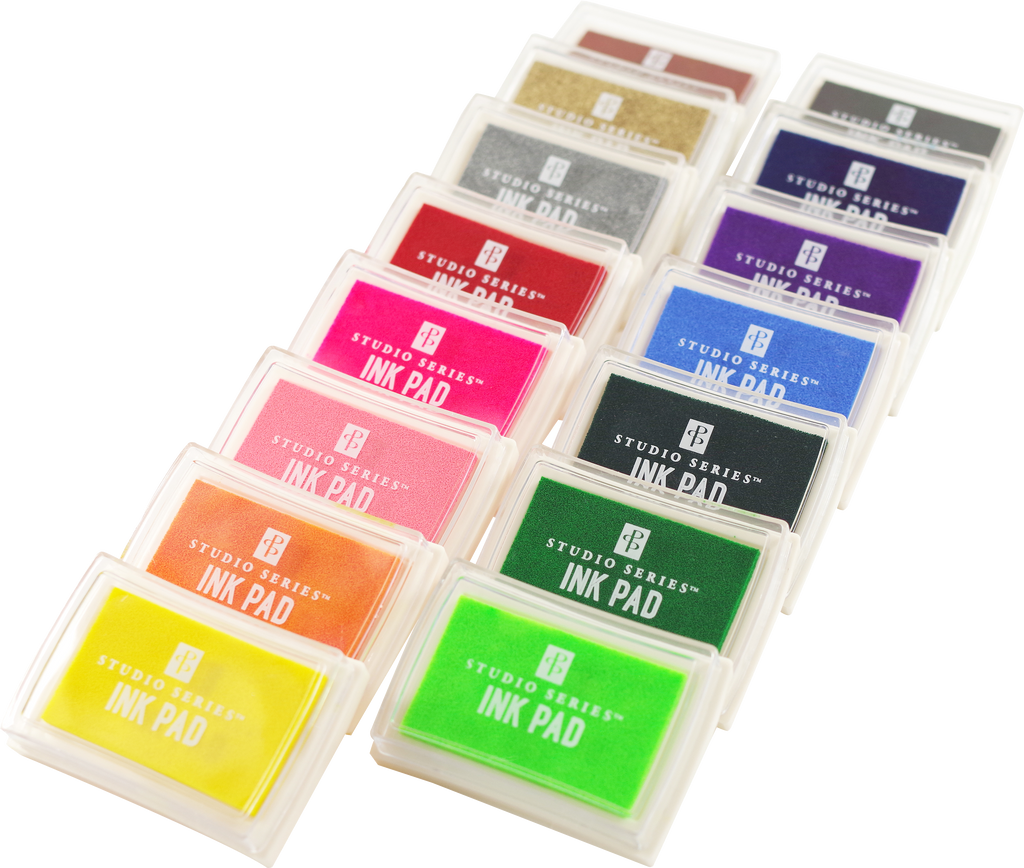The Studio Series Ink Pad Set features 15 vibrant dye ink colors — including yellow, green, orange, pink, purple, blue, black, silver, and gold — arranged diagonally in clear cases. Ideal for scrapbooking and crafts.