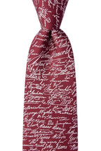 A close-up of the Declaration of Independence Signers Silk Tie showcases its maroon silk fabric adorned with white cursive signatures, forming a distinctive all-over pattern. Knotted and set against a plain white background, this tie makes a perfect gift for history enthusiasts or a stylish accessory for patriotic celebrations.