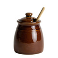 Handcrafted in Virginia, this brown ceramic Honey Pot features a lid and a wooden dipper resting inside.