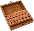 The Letterpress Stamp Set comes in a wooden box with an open lid, displaying rubber-tipped wooden stamps of A–Z, a–z, numbers 0–9, and an ampersand, all neatly arranged in rows.