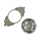 The Nickel Plated Tea Strainer, featuring a vintage-style lacy handle and matching round perforated sieve cup, is elegantly displayed on a white background — ideal for enjoying loose-leaf tea.