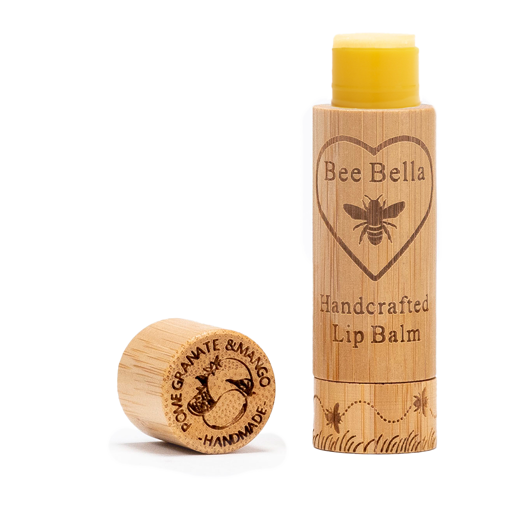 A wooden tube of Pomegranate Mango Lip Balm with its cap off beside it. The label shows a bee and heart, while the cap is engraved with "Pomegranate & Mango Handmade"—a nourishing beeswax lip balm.