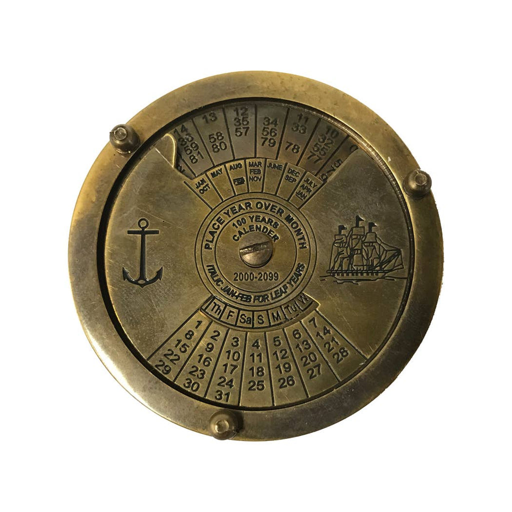 The Antiqued Solid Brass Compass is a round 100-year calendar in solid brass, engraved with numbers, months, and days. It has an anchor on the left, sailing ship on the right, and rotating parts to set years (2000–2099) and months for date calculation.