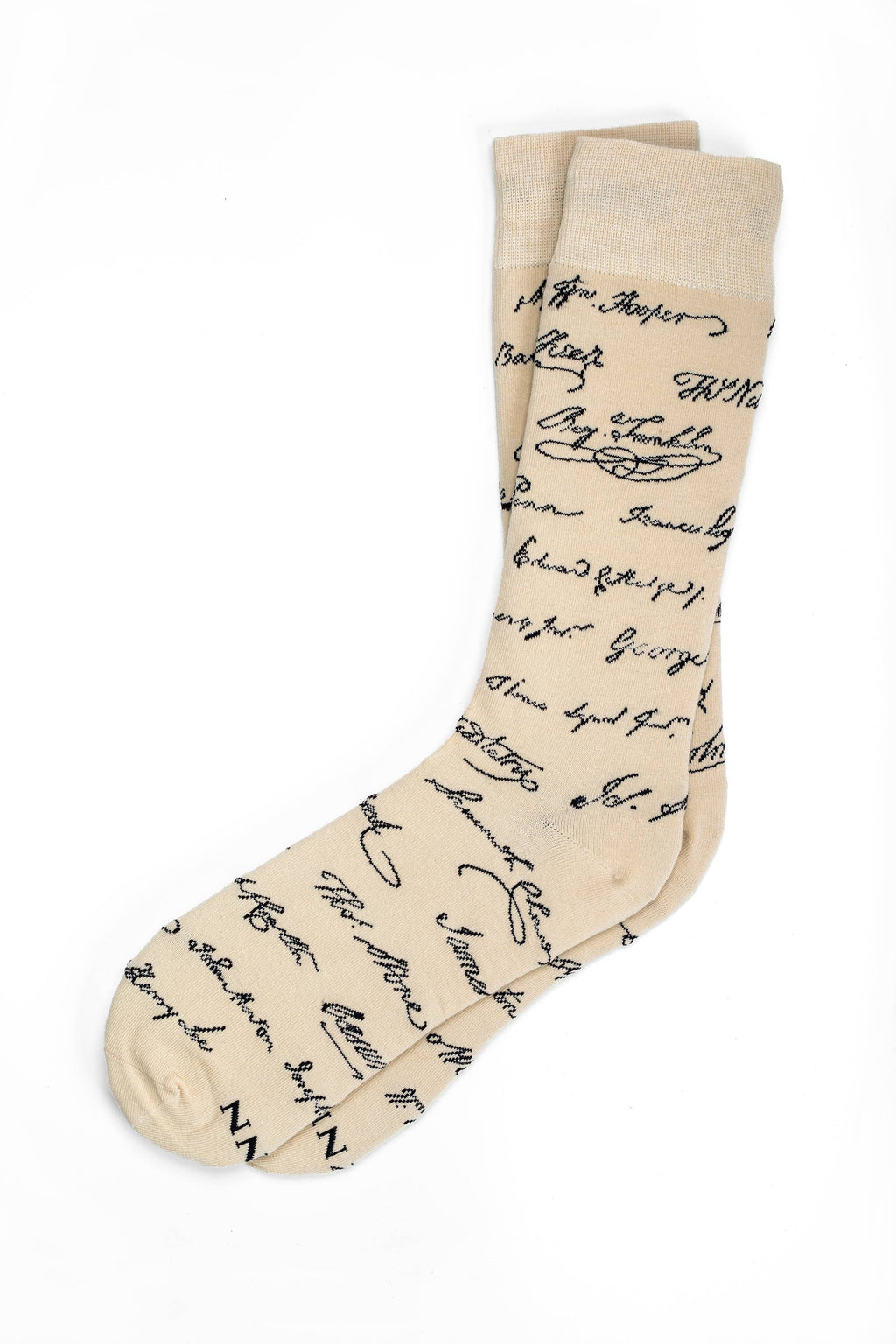 Introducing the Declaration Signers Crew Socks: beige crew socks featuring a repeating pattern of black cursive signatures reminiscent of the historic Declaration of Independence. These stylish socks add a subtle touch of patriotism to your wardrobe, with their signature motif set against a classic beige background. Presented here laid flat on a white backdrop.