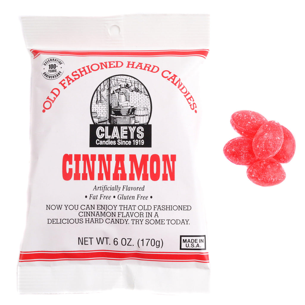 A white bag labeled "Cinnamon Old Fashioned Hard Candies" sits beside four red, oval cinnamon candies. The packaging features vintage-style branding with red and black text, evoking classic old fashioned candy charm.